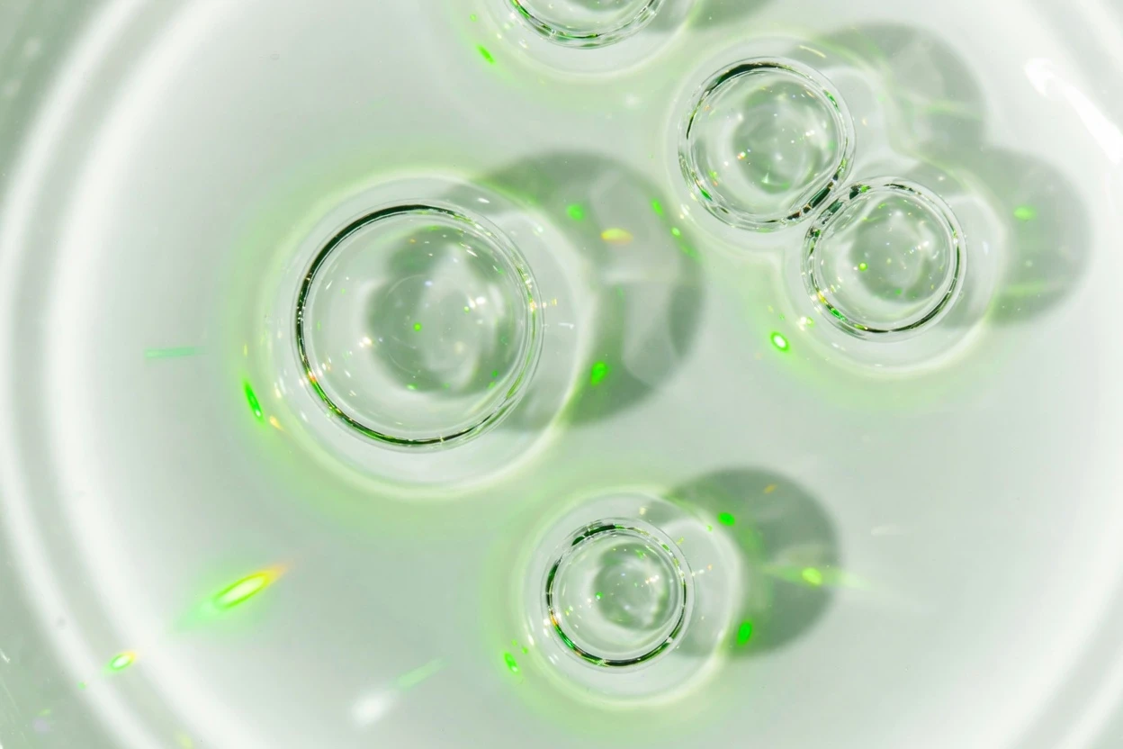 Clear bubbles in bright water with green light reflections.